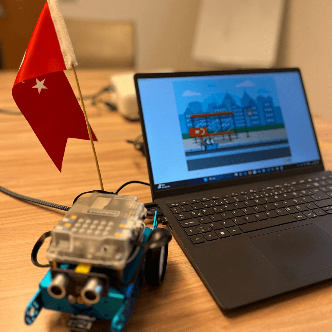 mBot robotu ve dizüstü ekranında mBlock'ta hazırlanmış Türk bayraklı bir sahne